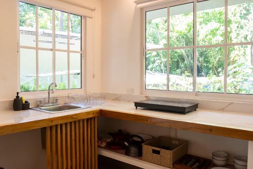 a kitchen with a sink and two windows at Jaguar Inn Bungalows in Puerto Viejo