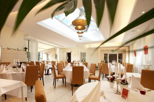 un restaurante con mesas y sillas blancas y tragaluz en Kreuz-Post Hotel-Restaurant-SPA, en Vogtsburg
