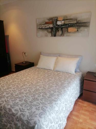 a bedroom with a bed with a white comforter at Casa dos lírios in São Teotónio