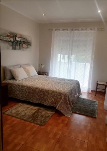 a bedroom with a bed and a large window at Casa dos lírios in São Teotónio