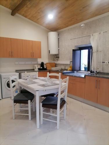 a kitchen with a white table and chairs in a kitchen at Casa dos lírios in São Teotónio
