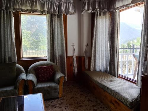 a living room with two chairs and two windows at Available for Kalam in Kalām