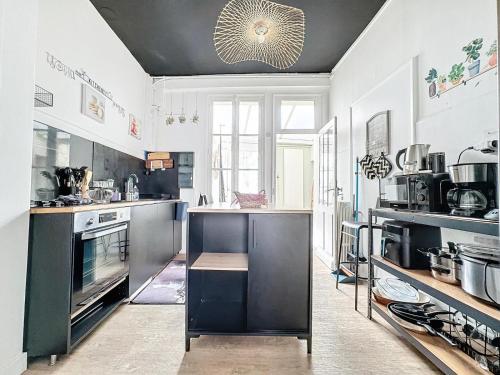 une grande cuisine avec des murs blancs et des appareils noirs dans l'établissement A1 Champagne Résidence - 200 m2 14 personnes 2 toilets 4 showers - hyper centre - Chalons en Champagne, à Châlons-en-Champagne