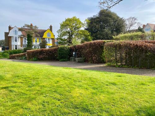 a house with a hedge in front of a yard at Garden Beach Apartment, Hunstanton Norfolk in Hunstanton