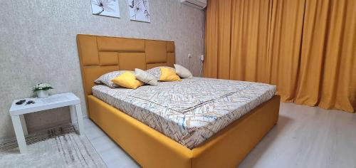 een slaapkamer met een groot bed met gele kussens bij 1 ком квартира в центре in Oral