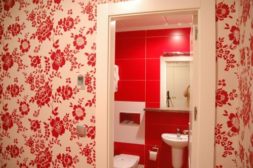 a red bathroom with a toilet and a sink at Hotel Ideal in Villarrobledo