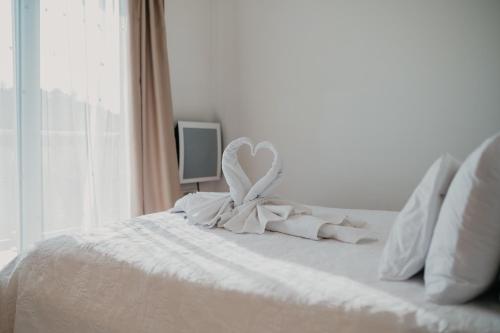 a white bed with a heart decoration on it at Lavender residence Villa Drage with pool and wellness in Drage