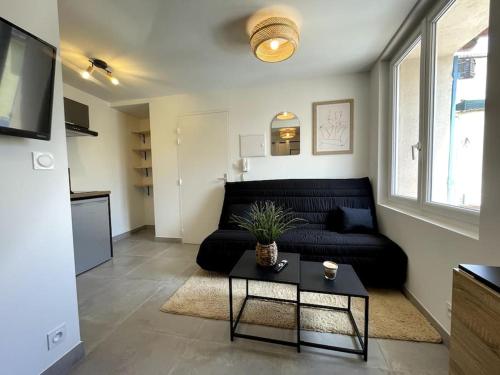un salon avec un canapé noir et une table dans l'établissement Studio cosy et climatisé, idéal pour 2 pers, à La Crau