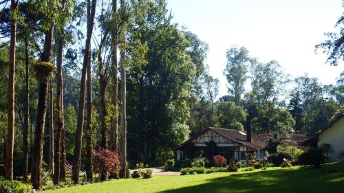a house in the middle of a yard with trees at Hotel Refazenda in Visconde De Maua