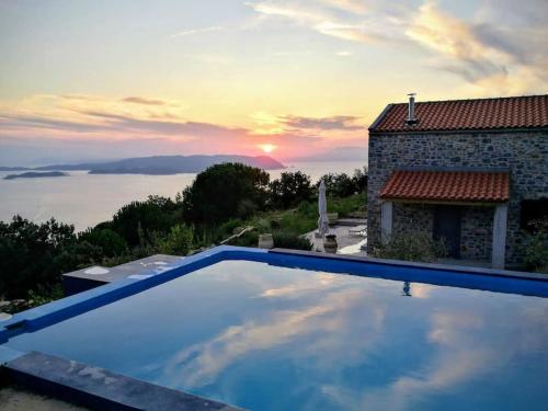 a swimming pool in front of a house with the sunset at Villa Vouno - luxury and privacy in the Aegean in Klíma