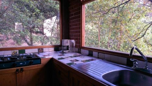 a kitchen with a sink and two large windows at Acogedor Bungalow en medio del bosque de Tepoztlan in Tlacotenco