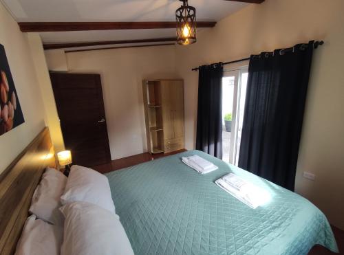 a bedroom with a green bed with a window at Rooftop "Montalvo" in Baños