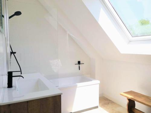 une salle de bain blanche avec un lavabo et une fenêtre dans l'établissement Piscine - Maison Moderne - Route des Plages, à Saint-Philibert