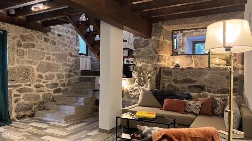 a living room with a couch and a stone wall at Cozy Galician Stone Farmhouse with Pool in Santo Tomé
