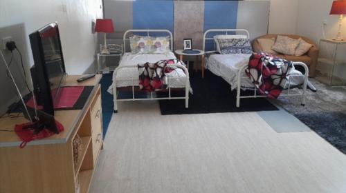 a bedroom with two beds and a tv and a couch at Spacious Townsville City Apartment in Townsville