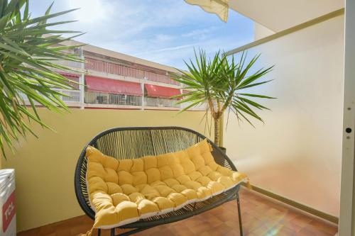 un canapé jaune assis sur un balcon avec un palmier dans l'établissement Apartment with Terrace walk to Beaches & Shopping, à Cannes