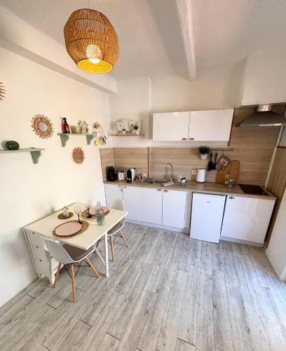 une cuisine avec des armoires blanches et une table dans une pièce dans l'établissement Studio terrasse Sanary centre ville rue piétonne, à Sanary-sur-Mer