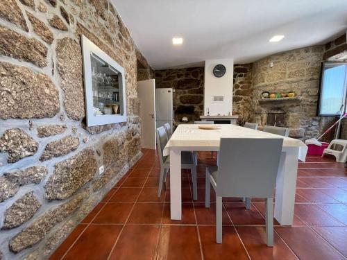 a kitchen with a white table and a stone wall at Casa Curto in Terras de Bouro