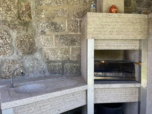 un bancone della cucina con lavandino e parete in pietra di Casa Curto a Terras de Bouro