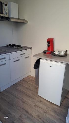 une cuisine avec des armoires blanches et un appareil rouge sur un comptoir dans l'établissement Magnifique Studio pas loin centre-ville, à Reims