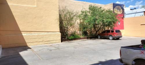 a red suv parked in a parking lot next to a building at Hoteles Santa Regina in Chihuahua