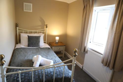 a bedroom with a bed and a window at Spacious House perfect for Families & Contractors - Free Parking & WIFI By ULTIMATE HOMES AWAY in Basingstoke
