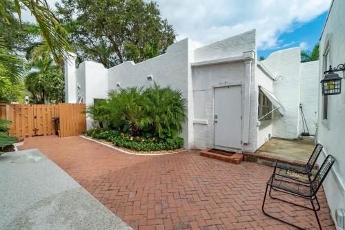 a white house with a brick patio with a chair at Garden Oasis in Flamingo Park in West Palm Beach