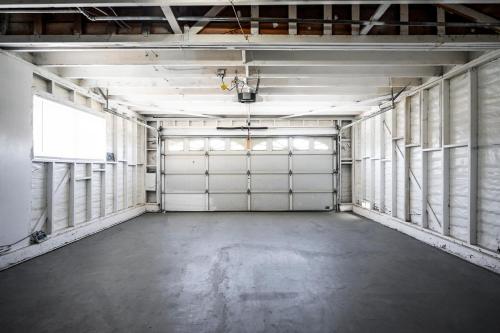 an empty garage with two white garage doors at Mins to Disney Chic 3BR with Arcade in Santa Ana