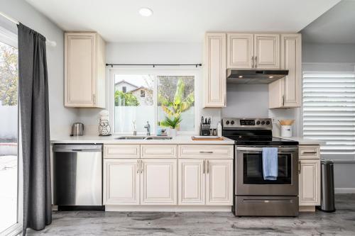 a kitchen with white cabinets and a window at Mins to Disney Chic 3BR with Arcade in Santa Ana