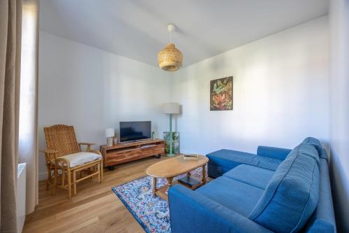 un salon avec un canapé bleu et une télévision dans l'établissement La Maison du Fleuve - Welkeys, à Dives-sur-Mer