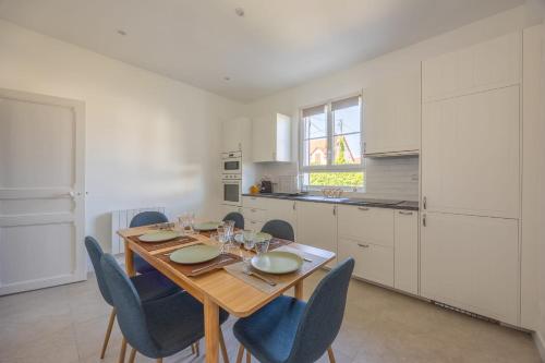 une salle à manger avec une table en bois et des chaises bleues dans l'établissement La Maison du Fleuve - Welkeys, à Dives-sur-Mer