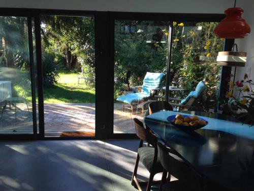 a dining room with a glass table and chairs and a patio at La Maison Bleue in Rezé