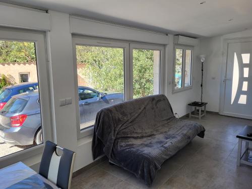 a living room with a couch and two windows at un petit coin de paradis in Cuges-les-Pins