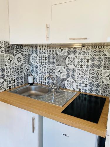 - une cuisine avec un évier et un mur en carrelage dans l'établissement Studio cosy bord de mer avec piscine et vue mer, à Saint-Cyprien
