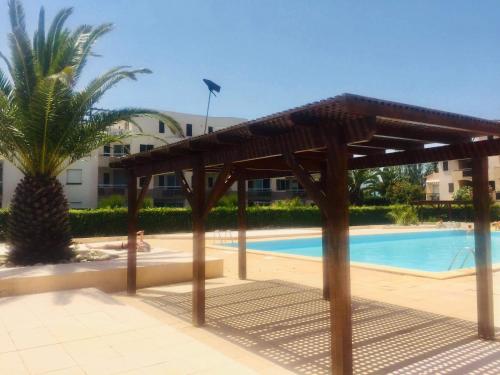 une pergola en bois à côté d'une piscine dans l'établissement Studio cosy bord de mer avec piscine et vue mer, à Saint-Cyprien