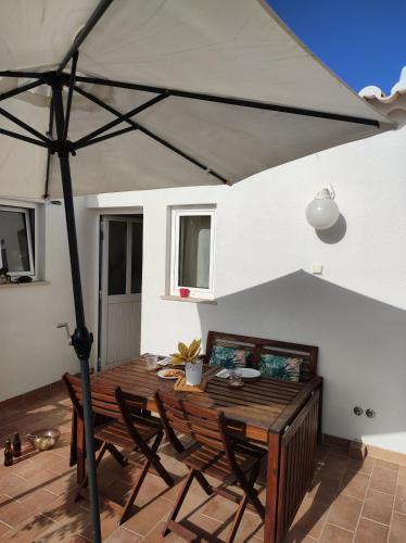 a wooden table with chairs and an umbrella at MONTE s PEDRO in Lagos