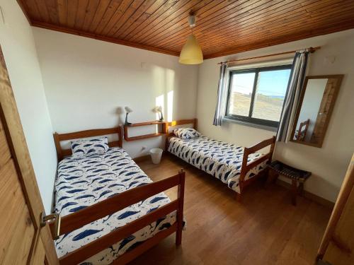 een slaapkamer met 2 bedden, een spiegel en een raam bij Longitude 31 House in Faja Grande