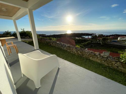 a white chair on a porch with a view of the ocean at Longitude 31 House in Faja Grande