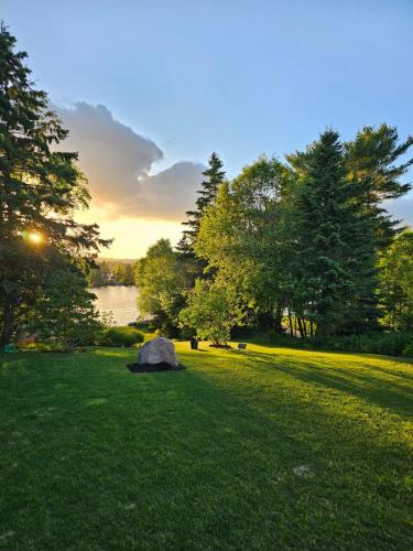 a rock in a field with a lake and trees at Tantallon Guest Room with Private Beach in French Village