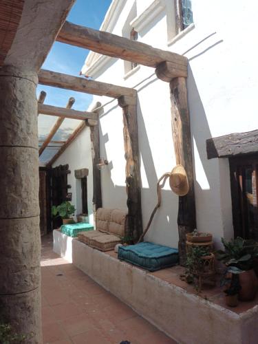 a porch of a white building with wooden beams at Guesthouse Un Poco Mas in Canillas de Aceituno