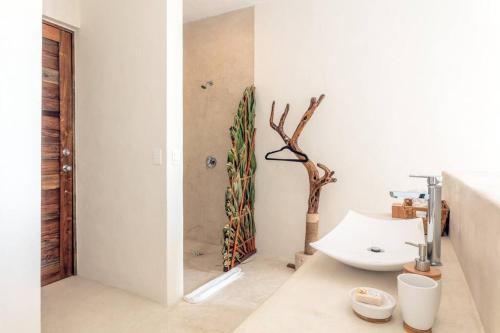 ein Badezimmer mit Waschbecken und einem Baum in der Ecke in der Unterkunft Crystal Nest SunSet View in Holbox