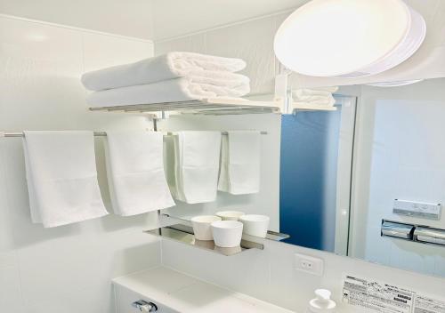 a bathroom with a mirror and white towels at TKP Sunlife Hotel in Fukuoka