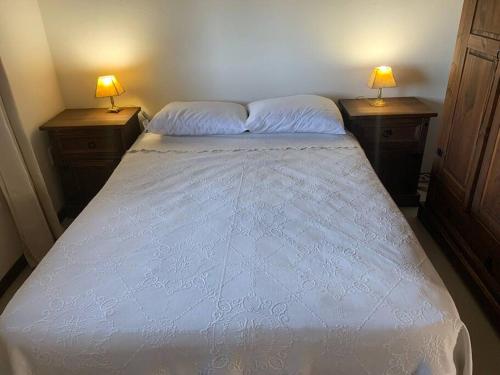 a bedroom with a white bed with two lamps on two tables at Casa MAAT Villa Serrana in Villa Serrana