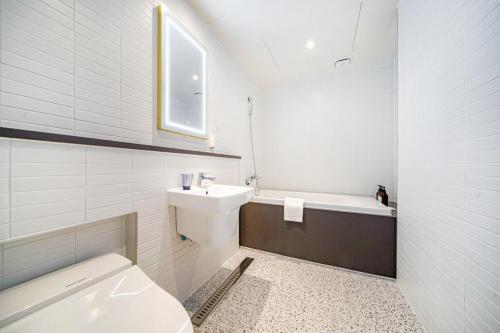 a bathroom with a toilet and a sink and a tub at Haeundae The Van Hotel in Busan