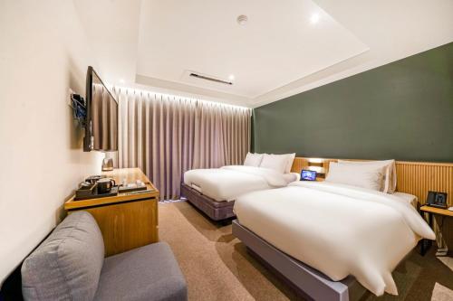 a hotel room with two beds and a couch at Haeundae The Van Hotel in Busan