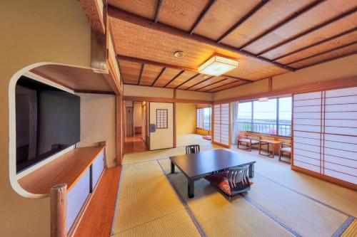 a living room with a table and a tv at AtamiOnsen Nagahamaen in Atami