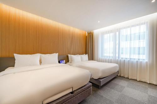a bedroom with two beds and a window at Haeundae The Van Hotel in Busan
