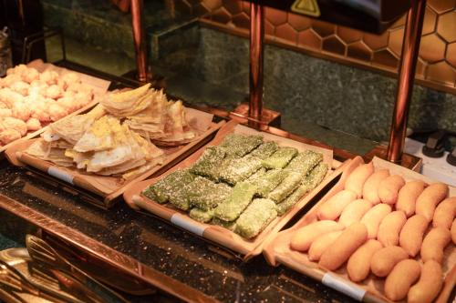 a buffet with different types of food on display at Zhangjiagang Pedestrian Street Manxin Hotel in Zhangjiagang
