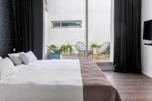 a bedroom with a large white bed and a balcony at Hotel BA Jardines Palermo in Buenos Aires