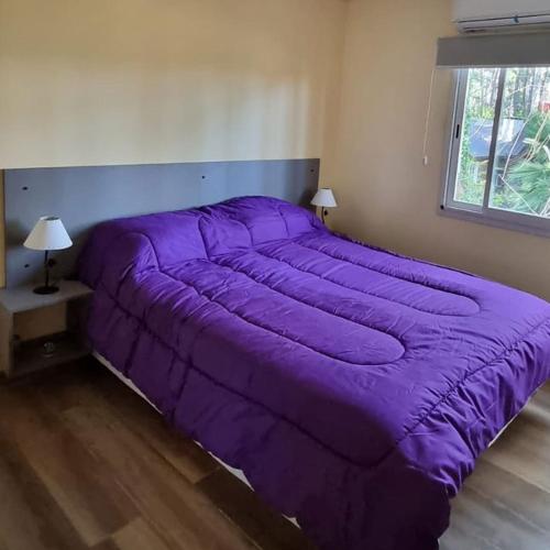 1 cama grande de color púrpura en una habitación con ventana en Los Menucos Mar Azul, en Mar Azul